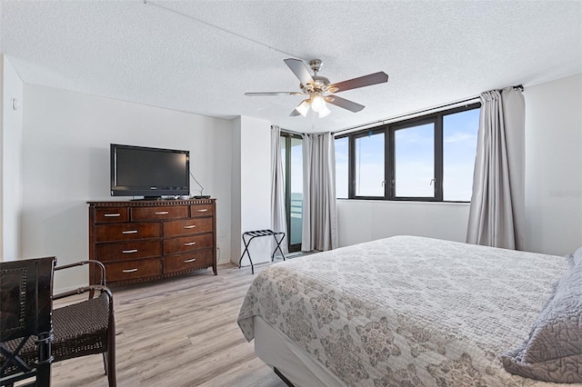 bedroom featuring ceiling fan, light hardwood / wood-style floors, and a textured ceiling