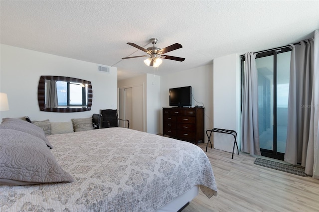 bedroom with ceiling fan, a textured ceiling, and light wood-type flooring