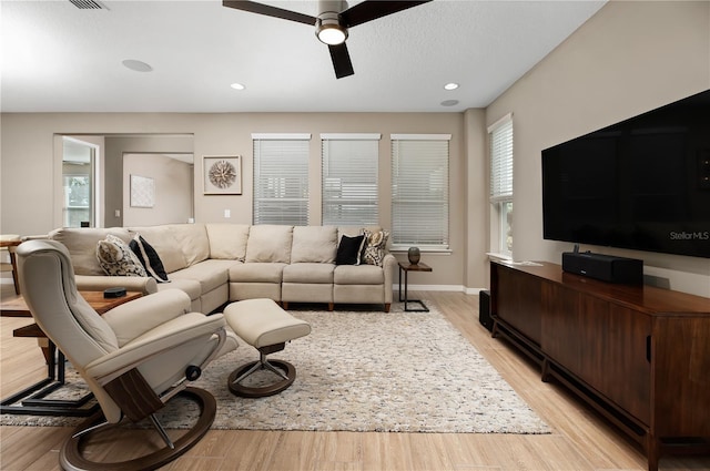 living room featuring ceiling fan, a textured ceiling, and light wood-type flooring