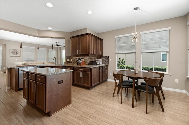 kitchen featuring sink, hanging light fixtures, a center island, light stone counters, and kitchen peninsula