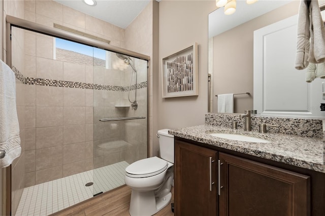 bathroom with vanity, wood-type flooring, a shower with door, and toilet