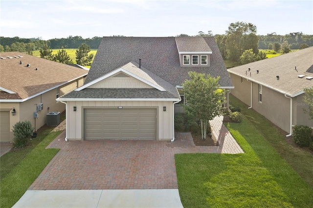 view of front of house with a garage, central AC unit, and a front lawn