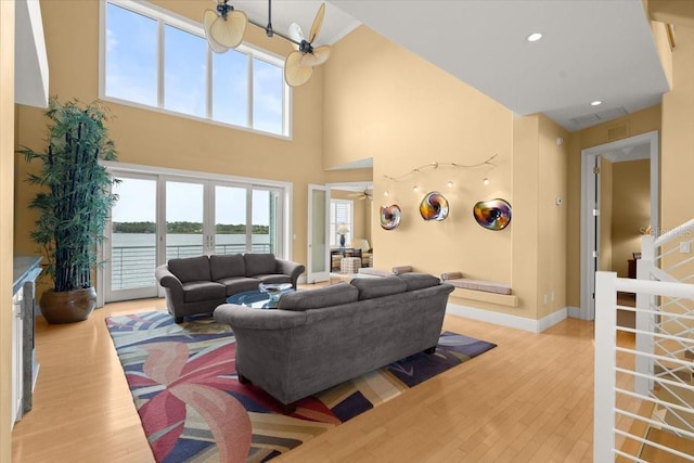 living room with light hardwood / wood-style floors, french doors, a healthy amount of sunlight, and a water view