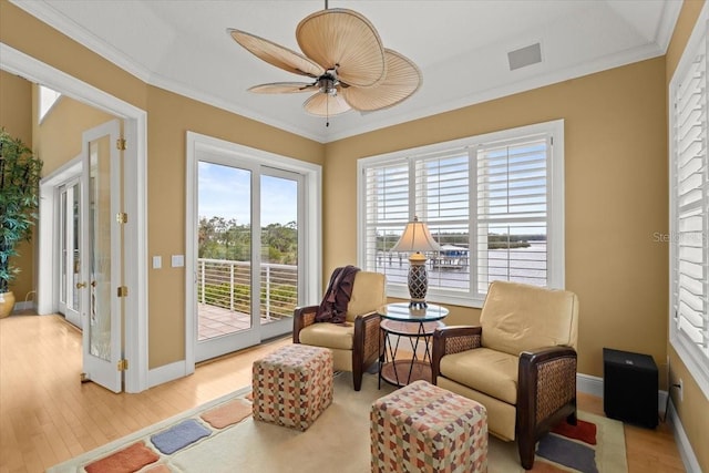 living area featuring crown molding, light hardwood / wood-style flooring, and ceiling fan