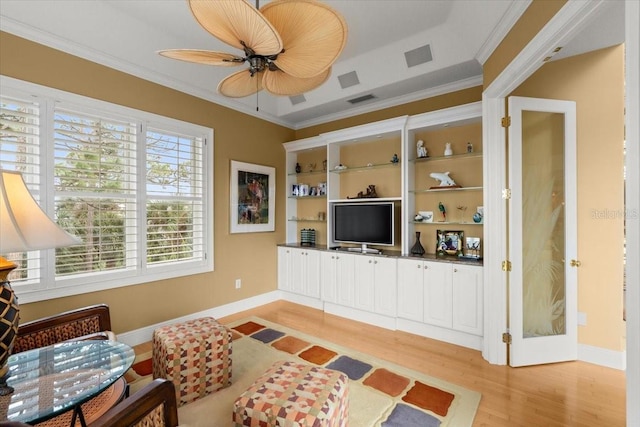 living room with crown molding, ceiling fan, and light wood-type flooring