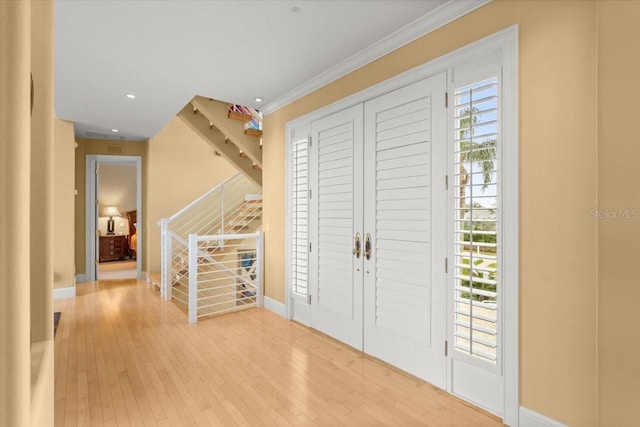 entryway with ornamental molding and light hardwood / wood-style flooring