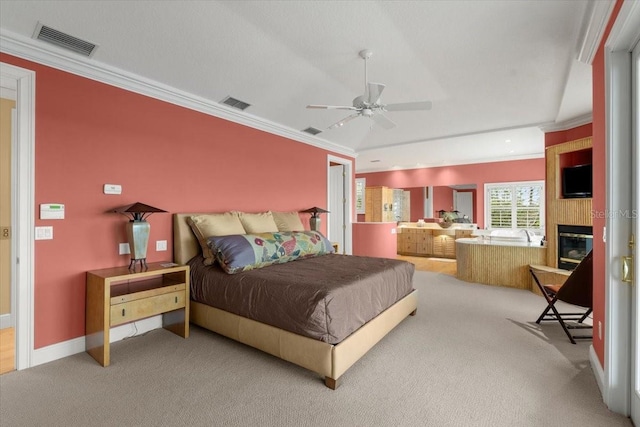 carpeted bedroom featuring crown molding, a large fireplace, and ceiling fan