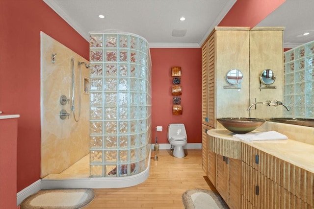 bathroom with wood-type flooring, vanity, tiled shower, toilet, and crown molding