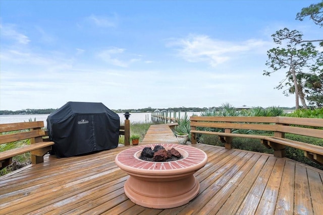 wooden terrace featuring a water view, area for grilling, an outdoor fire pit, and a dock