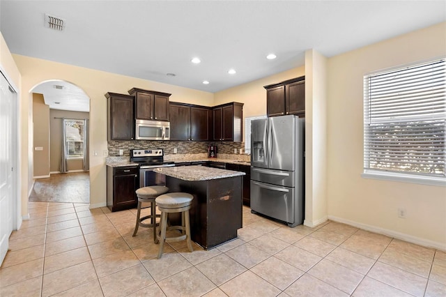 kitchen featuring dark brown cabinetry, a kitchen bar, stainless steel appliances, and a kitchen island