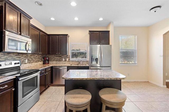 kitchen featuring a kitchen island, sink, a kitchen bar, stainless steel appliances, and dark brown cabinets