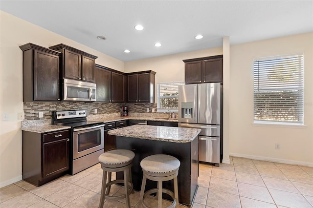 kitchen with a healthy amount of sunlight, appliances with stainless steel finishes, a center island, and backsplash