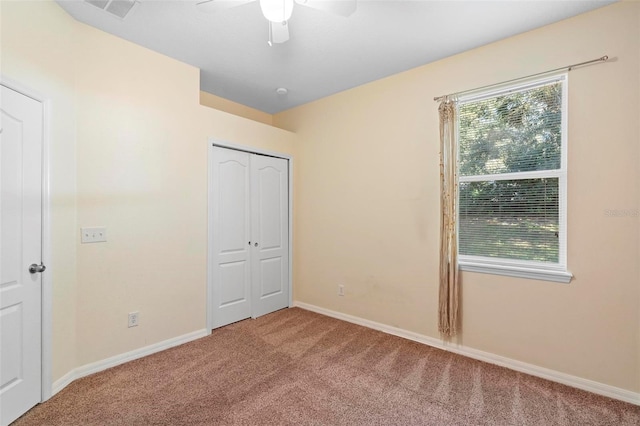 unfurnished bedroom featuring multiple windows, a closet, ceiling fan, and carpet flooring