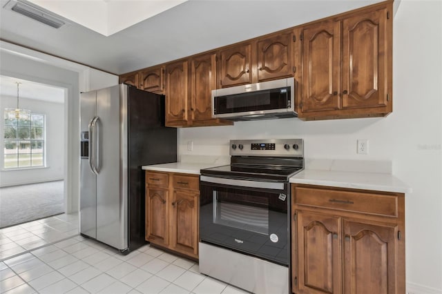 kitchen featuring light countertops, visible vents, an inviting chandelier, appliances with stainless steel finishes, and brown cabinetry