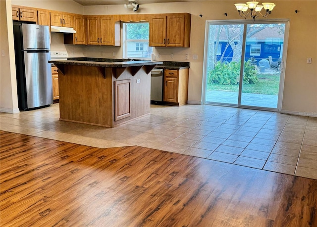 kitchen featuring stainless steel appliances, a kitchen bar, a kitchen island, and light hardwood / wood-style flooring