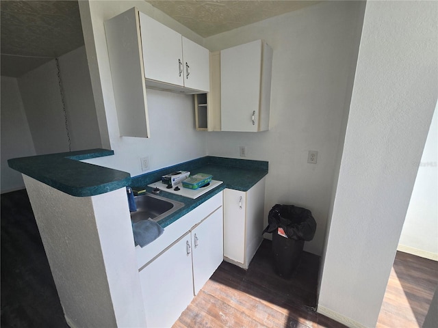 kitchen with dark wood-type flooring, sink, and white cabinets