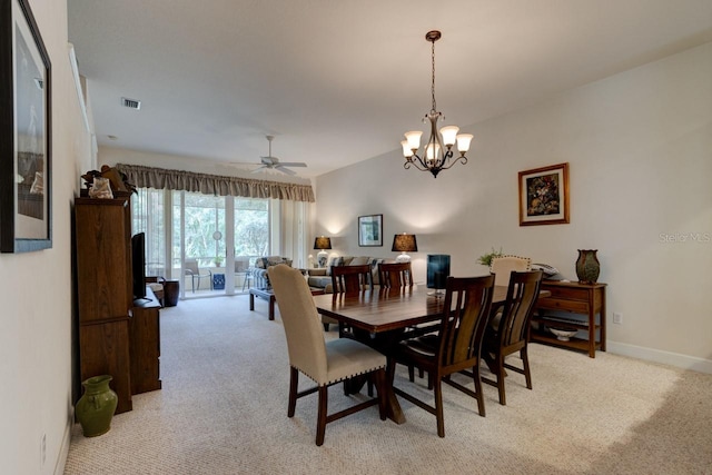 carpeted dining area featuring ceiling fan with notable chandelier