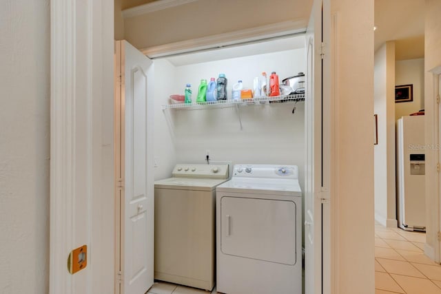 clothes washing area with washing machine and dryer and light tile patterned floors