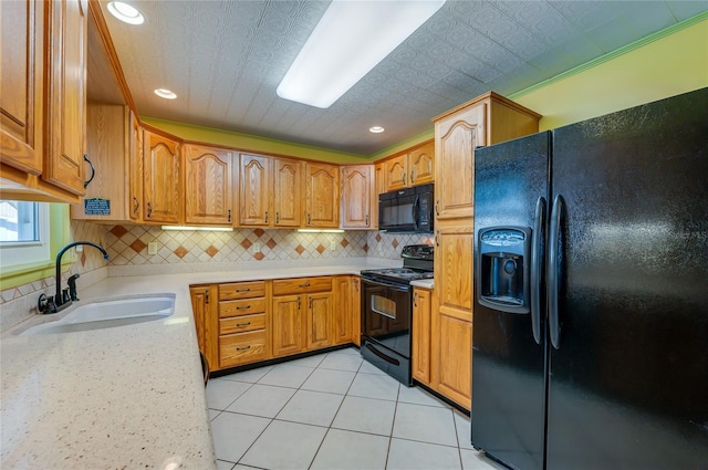 kitchen with tasteful backsplash, sink, light tile patterned floors, and black appliances