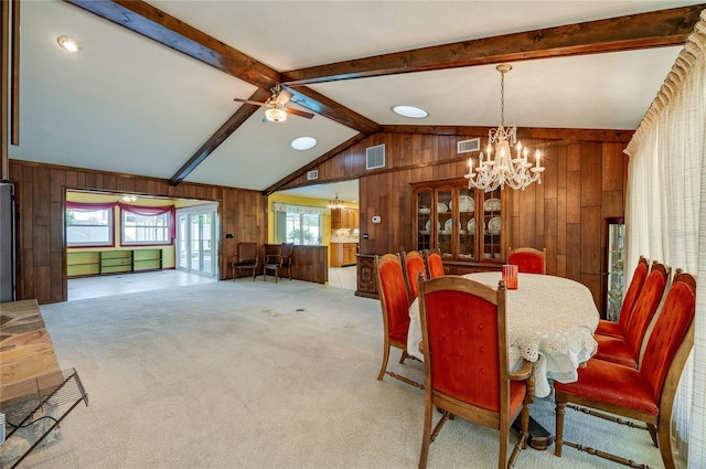 dining room with light carpet, vaulted ceiling with beams, ceiling fan with notable chandelier, and wood walls