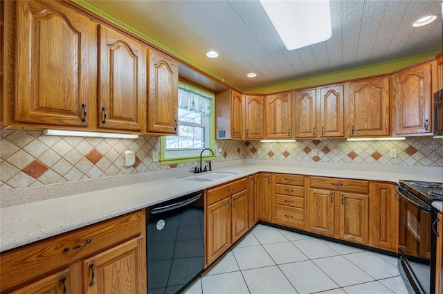 kitchen with tasteful backsplash, sink, light tile patterned floors, black appliances, and light stone countertops