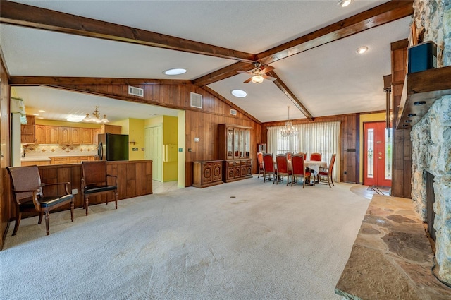 interior space with lofted ceiling with beams, ceiling fan with notable chandelier, and wood walls