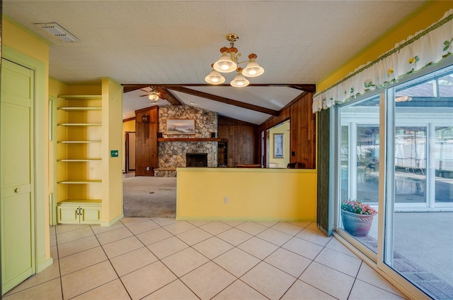 kitchen with light tile patterned flooring, wood walls, lofted ceiling with beams, built in features, and a fireplace