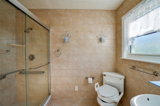 bathroom with tile walls, a shower with shower door, and toilet