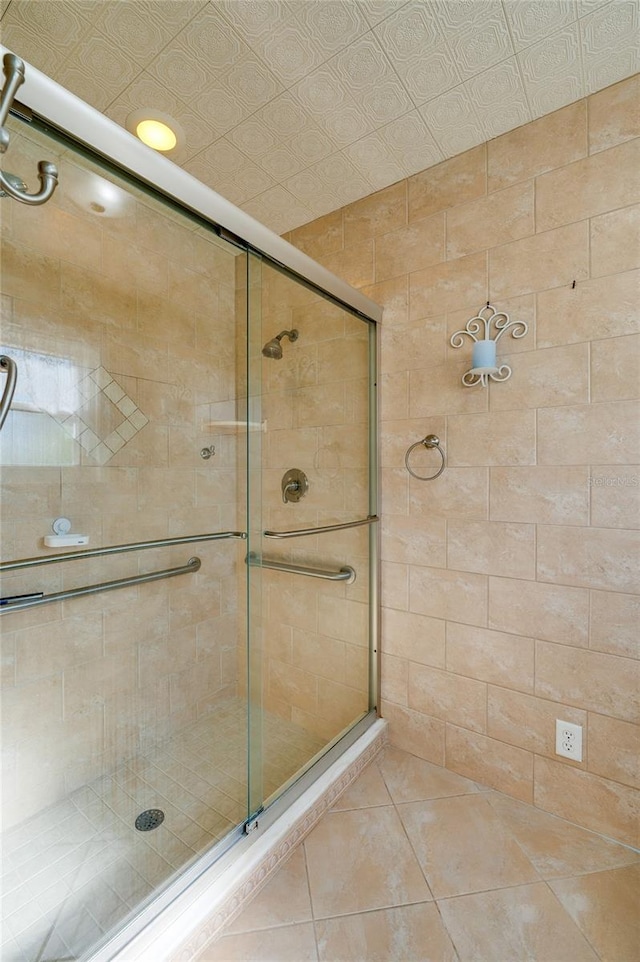 bathroom with an enclosed shower and tile patterned flooring