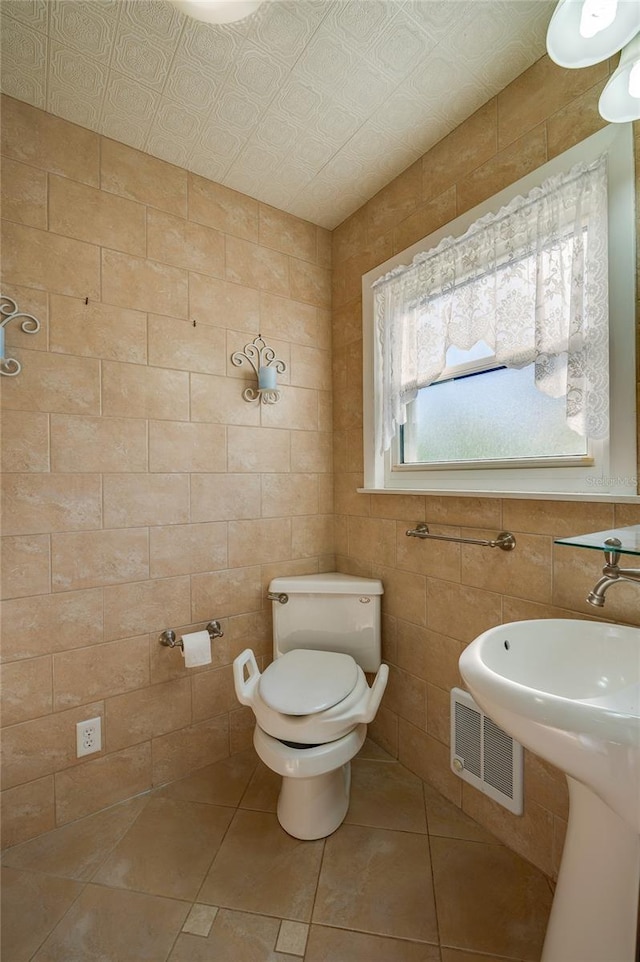 bathroom featuring tile patterned flooring, tile walls, and toilet