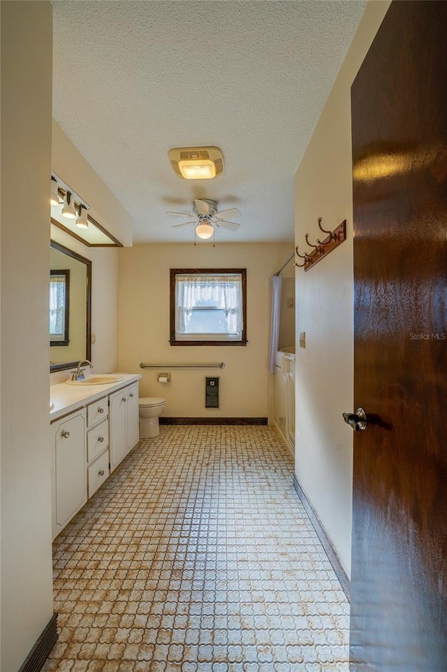 full bathroom featuring bathtub / shower combination, vanity, ceiling fan, toilet, and a textured ceiling