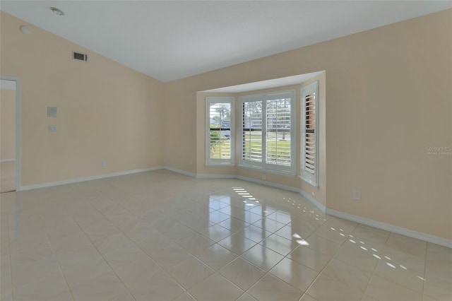 tiled empty room featuring vaulted ceiling