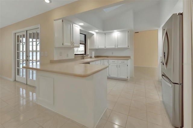 kitchen featuring french doors, light tile patterned floors, stainless steel fridge, kitchen peninsula, and white cabinets