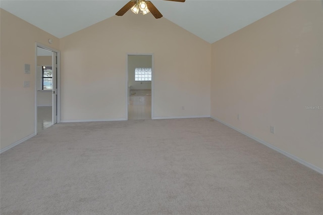 spare room featuring vaulted ceiling, plenty of natural light, light colored carpet, and ceiling fan