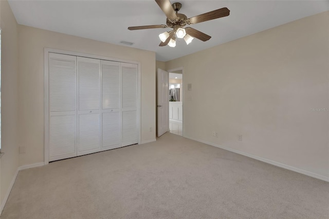 unfurnished bedroom with ceiling fan, a closet, and light carpet