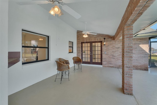 unfurnished room with vaulted ceiling, french doors, ceiling fan, and brick wall