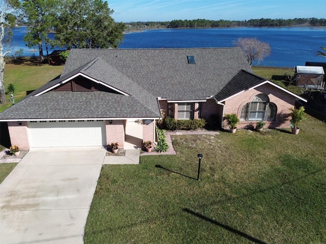 ranch-style house with a garage, a water view, and a front yard