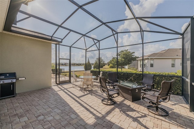 view of patio featuring a water view, a grill, a fire pit, and glass enclosure