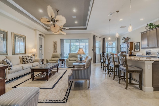 tiled living room with crown molding, ceiling fan, and a tray ceiling