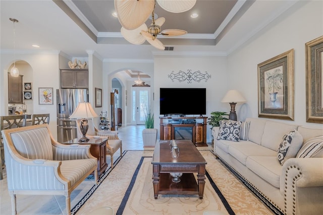 living room with crown molding, light tile patterned flooring, ceiling fan, and a tray ceiling