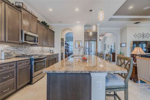 kitchen with stainless steel appliances, an island with sink, and a breakfast bar