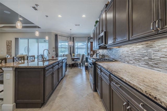 kitchen with pendant lighting, sink, a kitchen island with sink, stainless steel appliances, and light stone counters