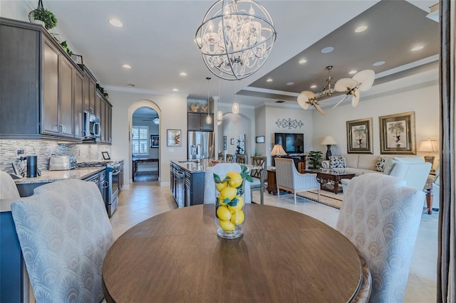 dining room featuring ornamental molding, a raised ceiling, ceiling fan with notable chandelier, and light tile patterned floors