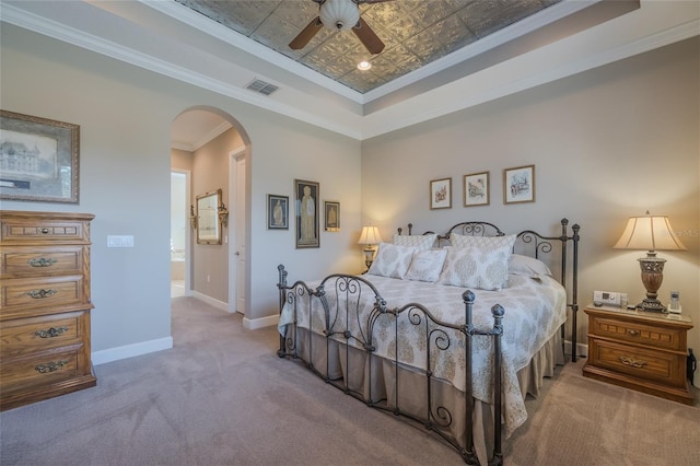 bedroom with crown molding, light colored carpet, ceiling fan, and a tray ceiling