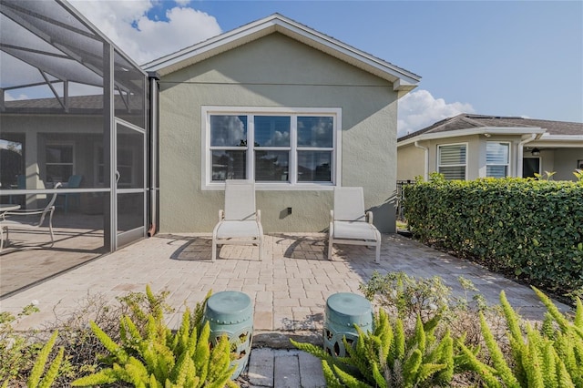 rear view of property featuring a patio and glass enclosure