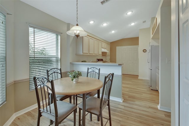 dining room with lofted ceiling and light wood-type flooring