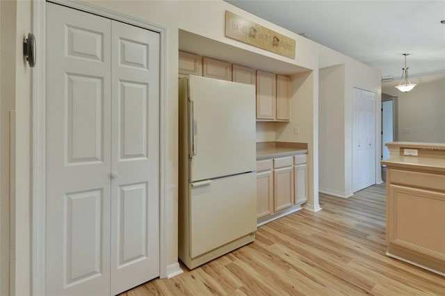 kitchen with pendant lighting, light wood-type flooring, light brown cabinets, and white fridge