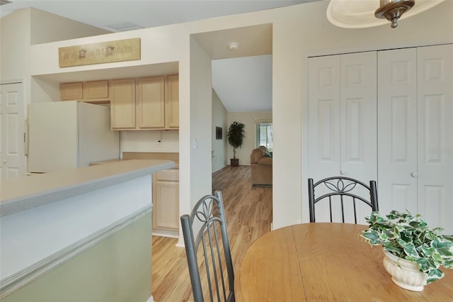 dining room with vaulted ceiling and light hardwood / wood-style flooring