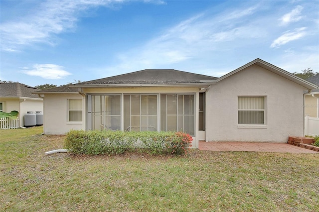 rear view of house with a sunroom, a patio area, and a lawn