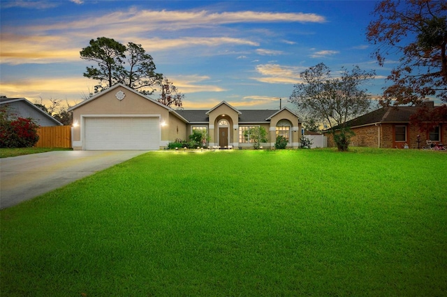 single story home featuring a garage and a lawn